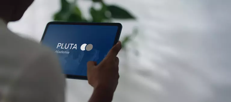 Symboldbild PLUTA Akademie – Tablet in der Hand mit dem Logo der PLUTA Akademie